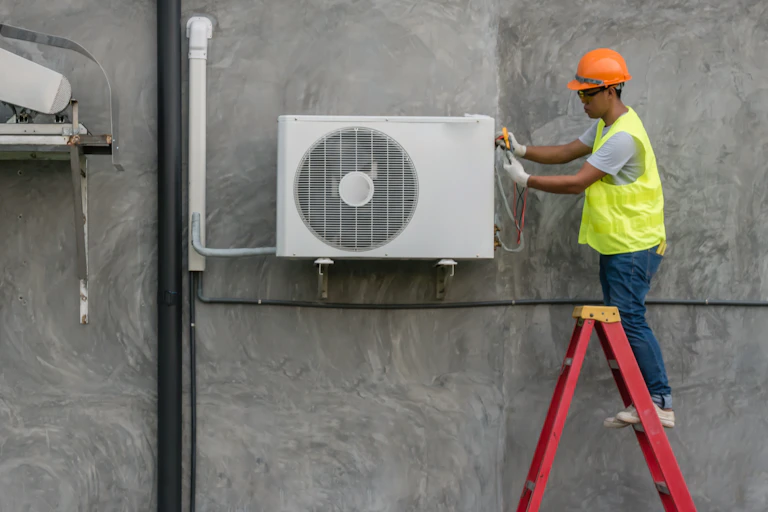 man in high-vis vest fixes air conditioning unit