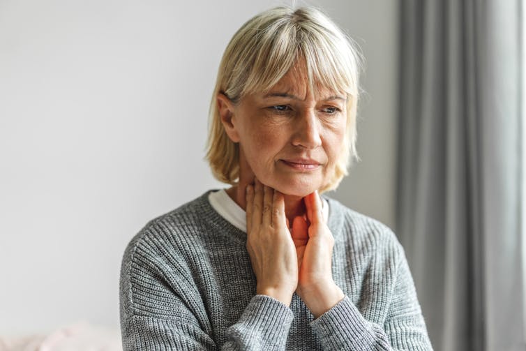 Older woman holds her throat