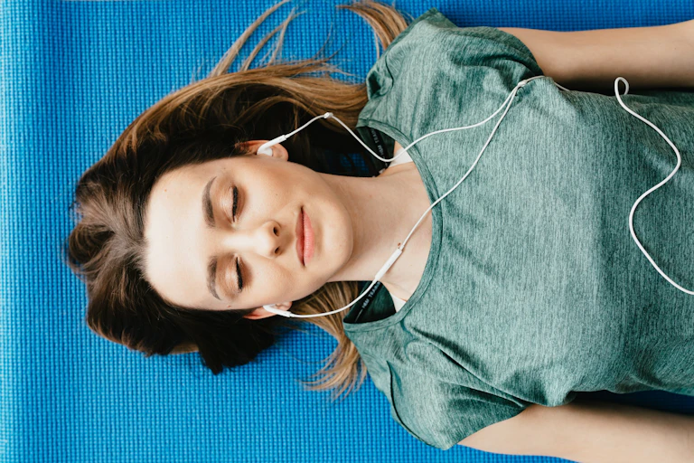 Woman asleep on yoga mat wearing earphones
