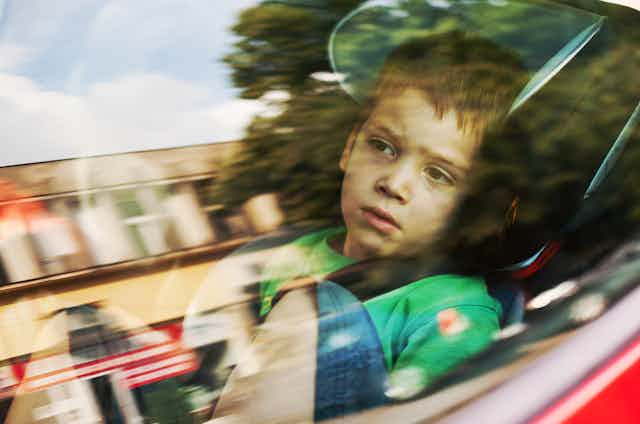 A boy looking bored in a car