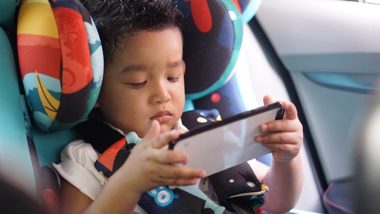 A child on a smartphone in a car