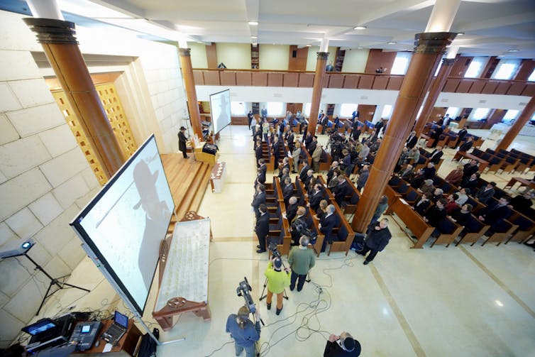 A room with many people gathered in a square looking forward.