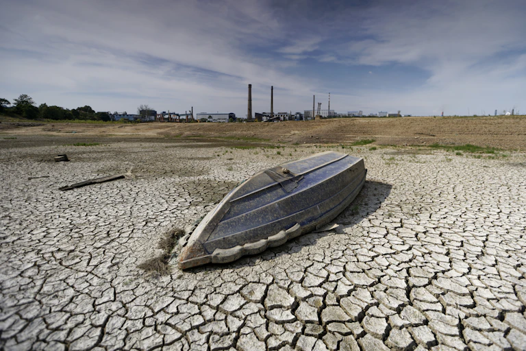 An overturned boat in a dry, cracked river bed.