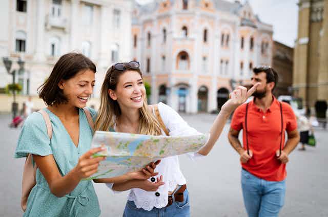 Young women looking at map in city