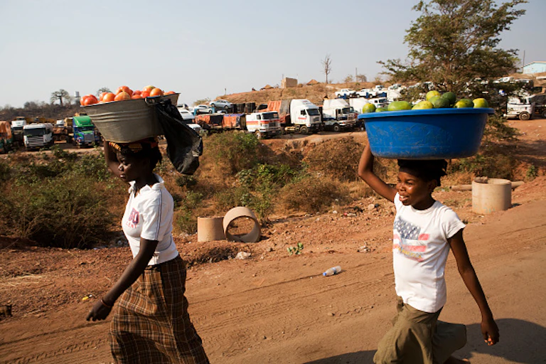Two women carrying goods on their heads