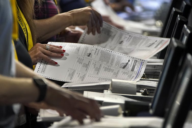 The hands of several people holding ballots and counting them.