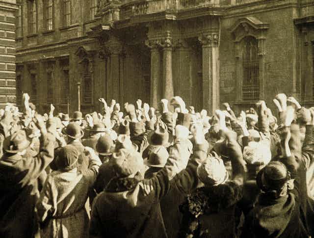 Movie still of a mass of people gathered with their fists in the air.