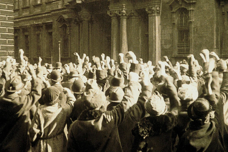 Movie still of a mass of people gathered with their fists in the air.