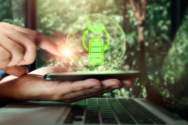 Hand with phone and laptop, battery, emissions