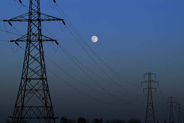 Electricity pylons at night with moon