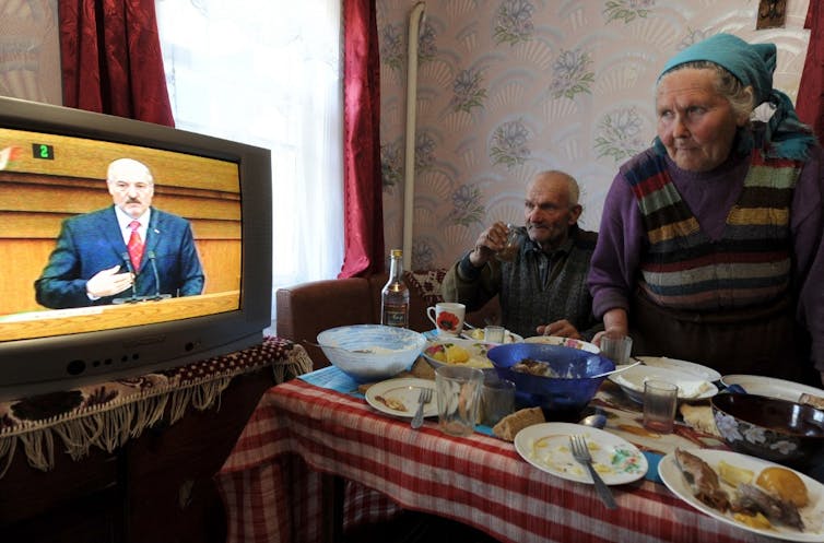 Un couple âgé regarde la télévision qui diffuse un discours d’Alexandre Loukachenko