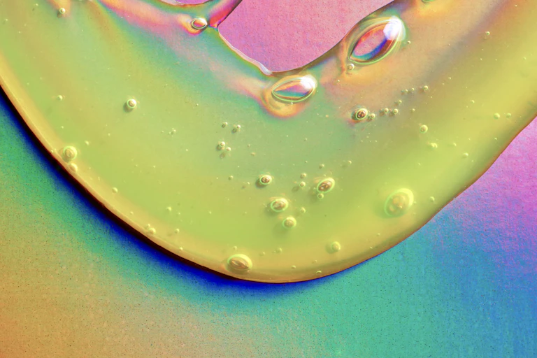 Close up of yellow-green slime dripping down a holographic foil