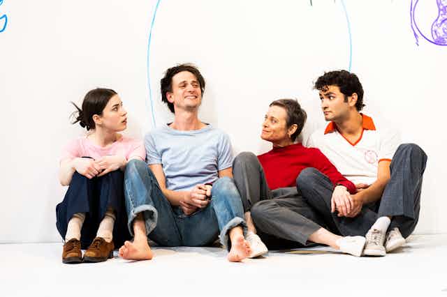 Four people sit on a white stage