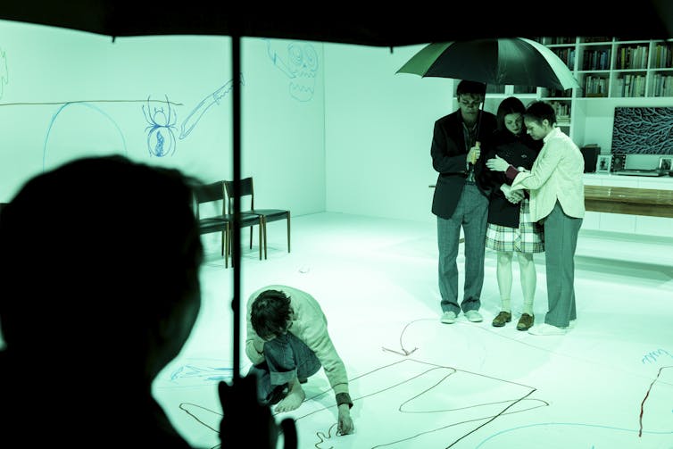 A family gathered under an umbrella.