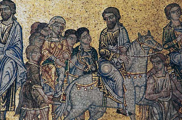 A mosaic with a gold-colored background shows men and women in robes, some riding horses.