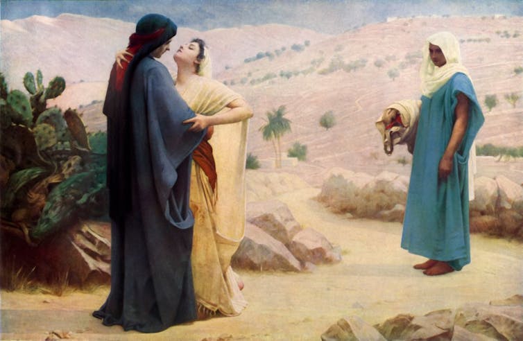 A painting shows two women in robes embracing in the desert, while another woman looks on.