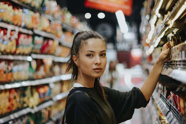 Young woman picking product off supermarket shelf