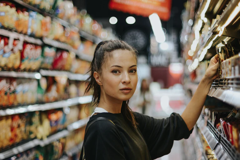 Young woman picking product off supermarket shelf