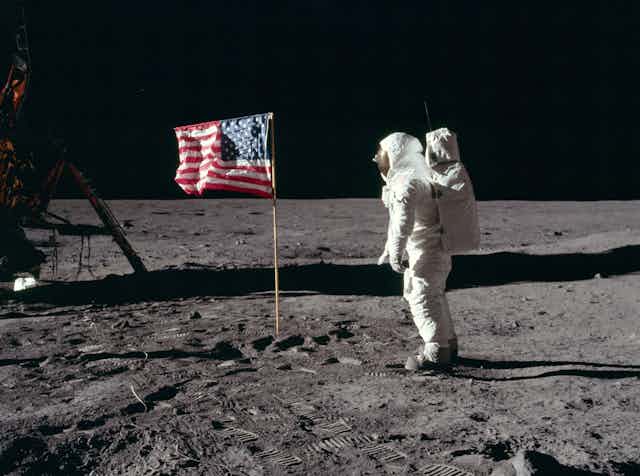 Un astronaute en combinaison spatiale salue le drapeau américain sur la Lune.