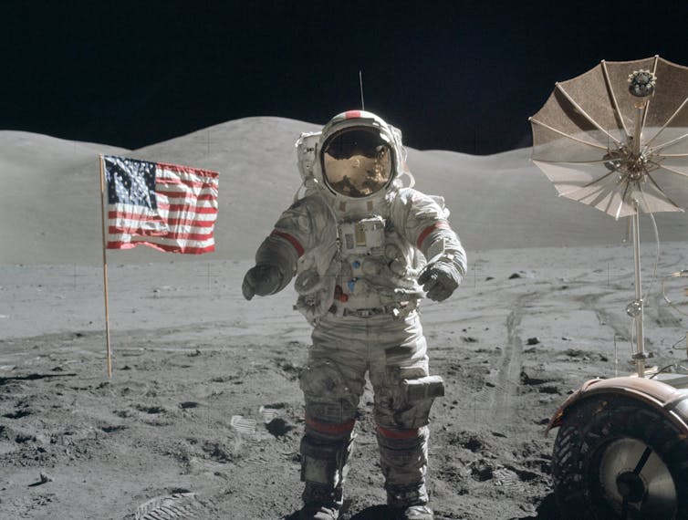 Eugene Cernan sur la Lune en combinaison devant le drapeau américain