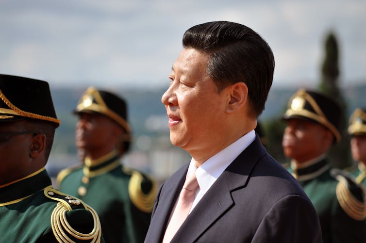 A man in a suit in front of uniformed soldiers.