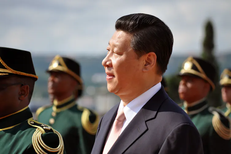 A man in a suit in front of uniformed soldiers.