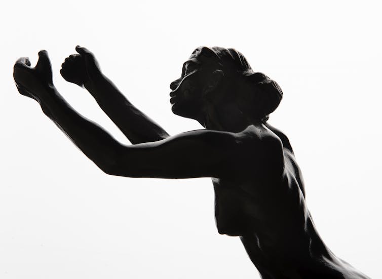 A small bronze statue of woman holding up her arms imploringly.