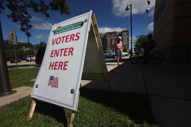 A large sandwich board that says 'Voters enter here' outside a building.