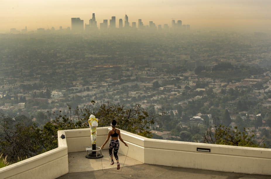 A woman jumps rope at an overlook of Los Angeles, where the city is shrouded in wildfire smoke.