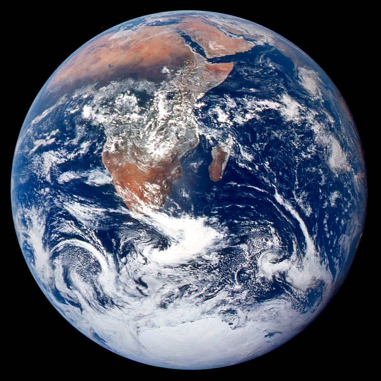 A complete view of Earth - a blue and green planet with swirls of clouds - on a black background