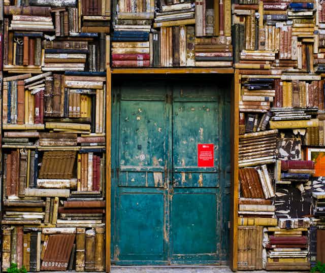 A turquoise door set in a wall full of books