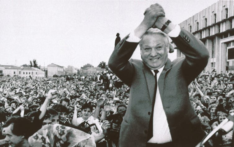 Man cheering himself in front of a large crowd, facing the camera, away from the crowd