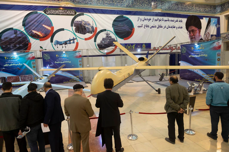 Seven men looking at an exhibit of drones.