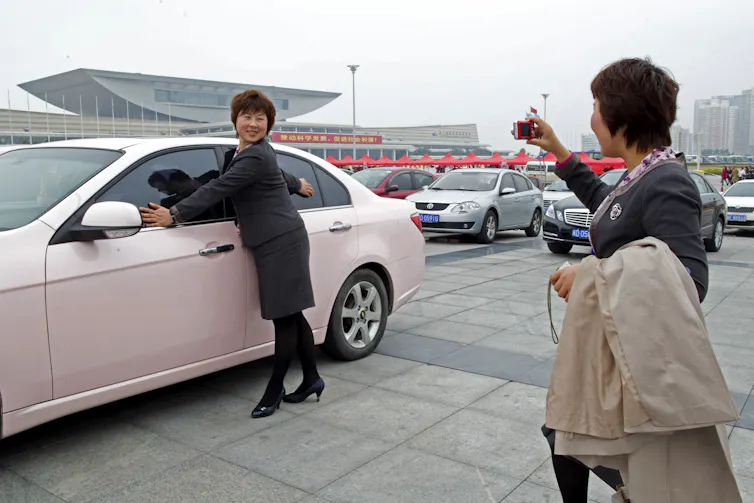 Salespersons from Anhui Province, China, pose for pictures in front of a pink sedan, an award for the best sales team, during the Mary Kay China Leadership Conference on February 20, 2011, in Xiamen, Fujian Province, China.