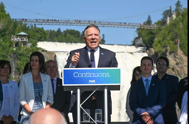 François Legault speaking at podium in front of candidates and waterfall