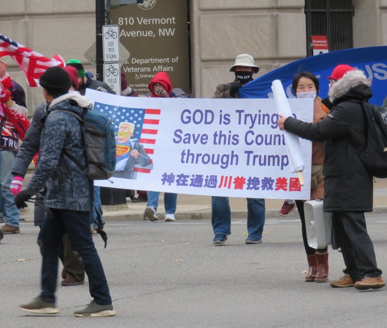 People march with a banner saying 'God is trying to save this country through Trump'