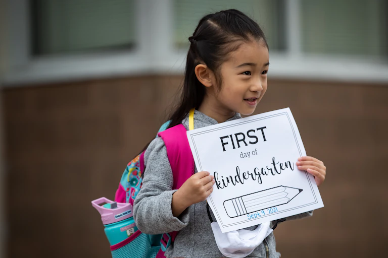 A child is seen holding a sign that says 'first day of kindergarten'