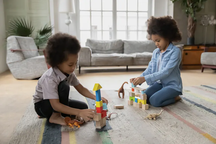 Children seen sitting on the floor playing with blocks.