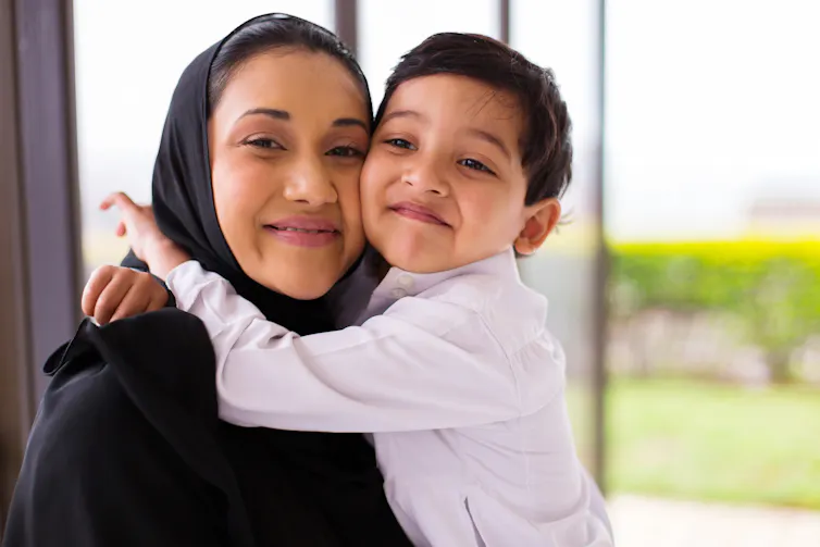 A mother and son hug side-to-side.