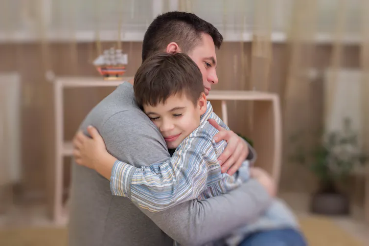 A father hugs a boy.