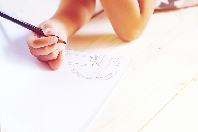 A child's hand seen drawing a picture.