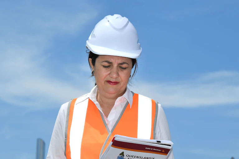 Women in hardhat and hi-viz looks at plan