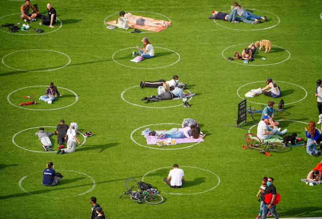 People lie on grass inside painted circles