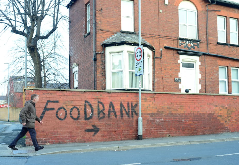 Man walking past a graffiti sign for a food bank