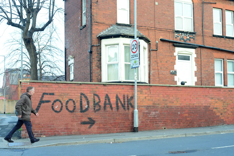 Man walking past a graffiti sign for a food bank