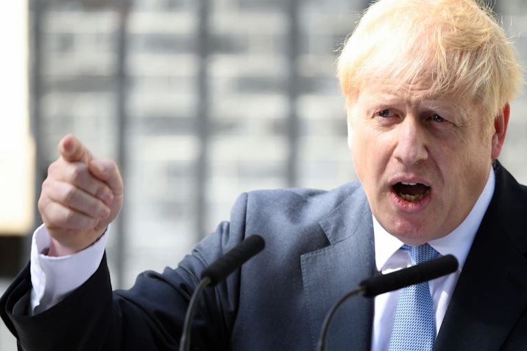 Close up of Boris Johnson gesturing with a pointed finger and speaking into a microphone outside of Downing Street