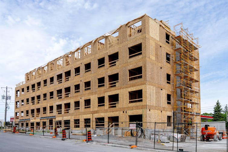 The wooden frame of an incomplete mid-rise building that is five storeys tall.