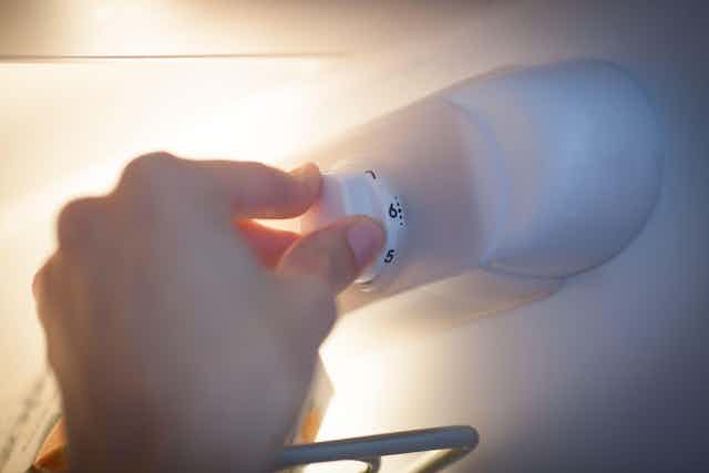 Person adjusting the fridge thermostat