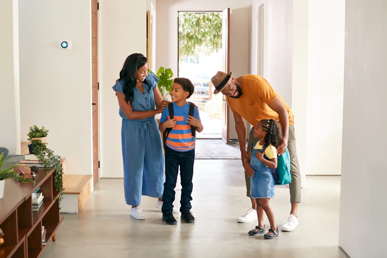 Parents with two children wearing backpacks in front of an open door