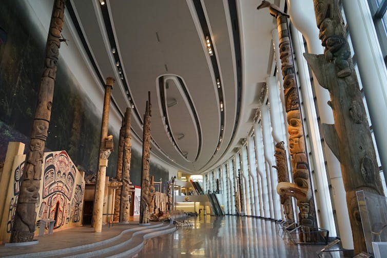 Totem poles lines a hallway inside a building.